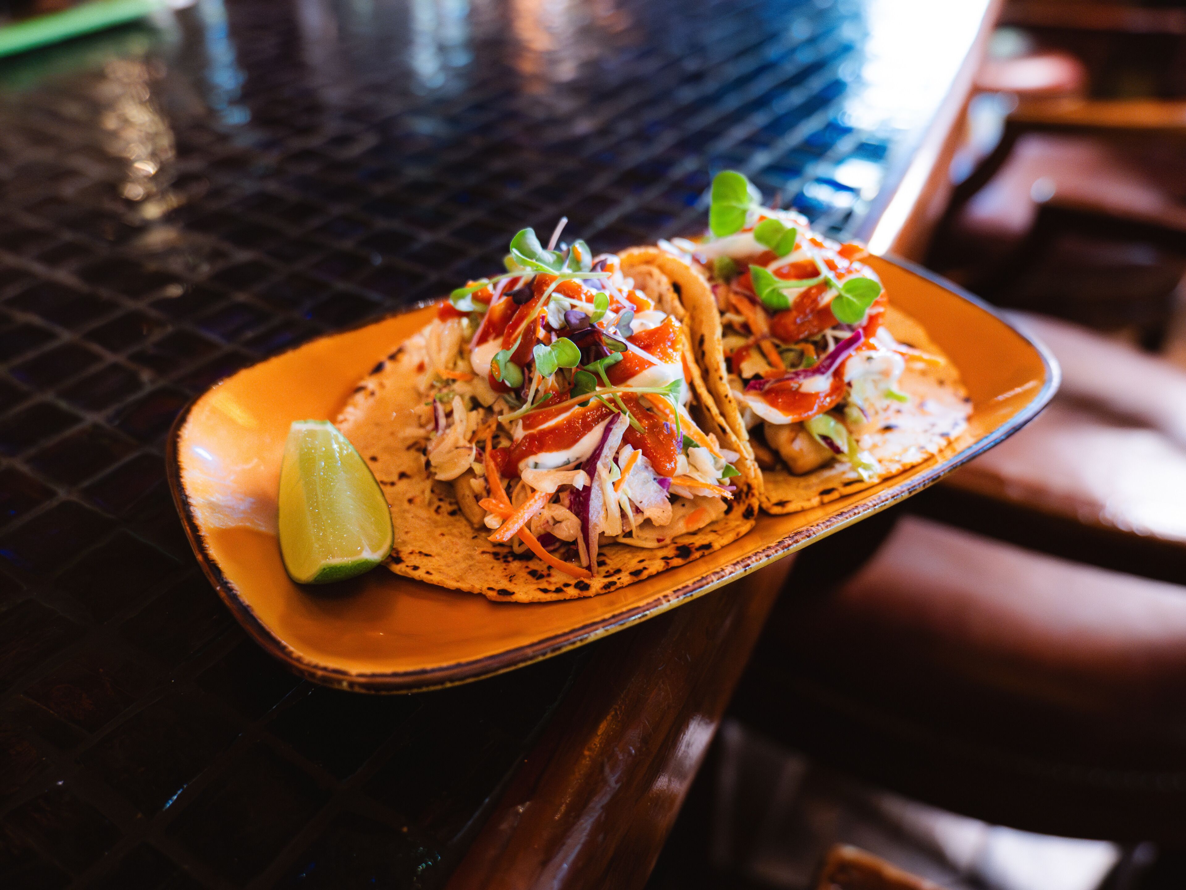 Dos tacos en un plato con una cuña de limón.