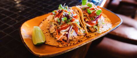 Dos tacos en un plato con una cuña de limón.