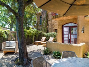 A patio area with wicker furniture, a stone wall, and a red door.