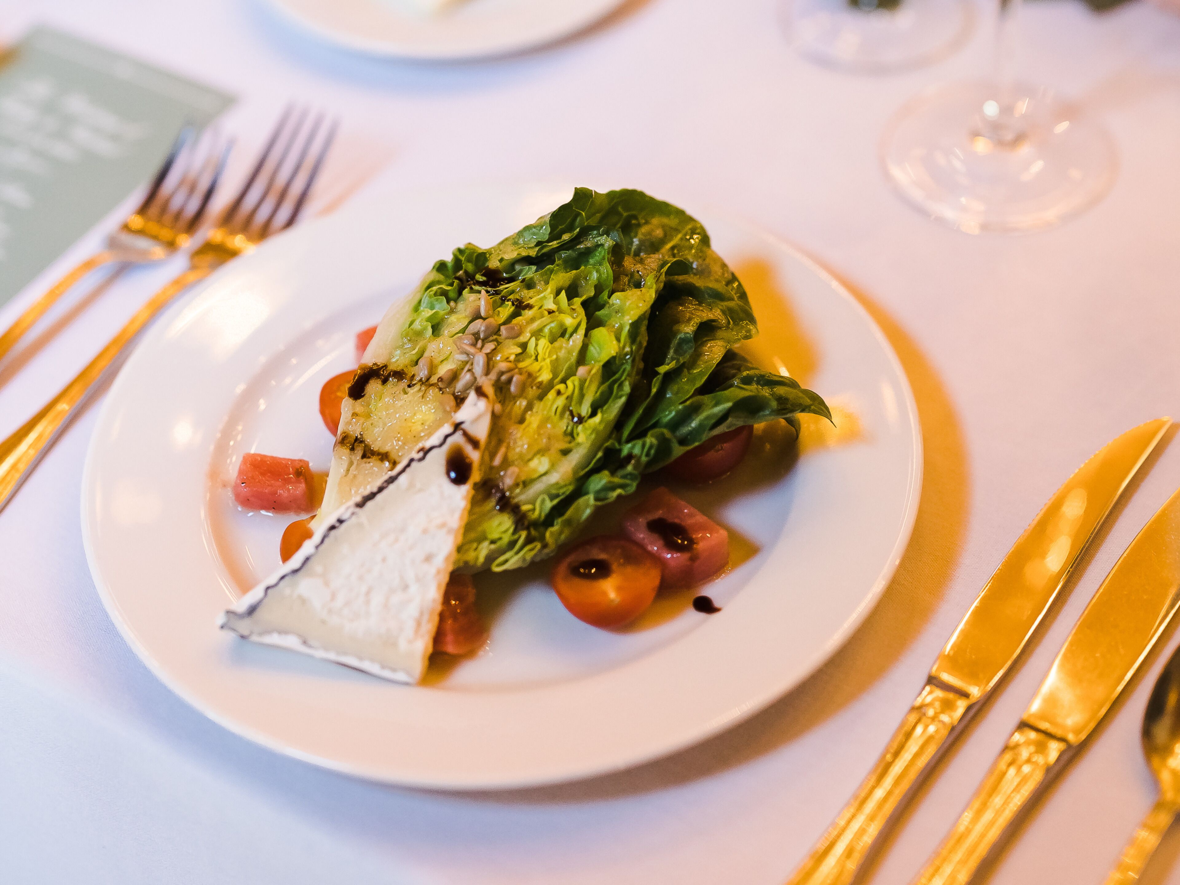A plate of food with a piece of cheese, lettuce, and tomatoes on a white plate.