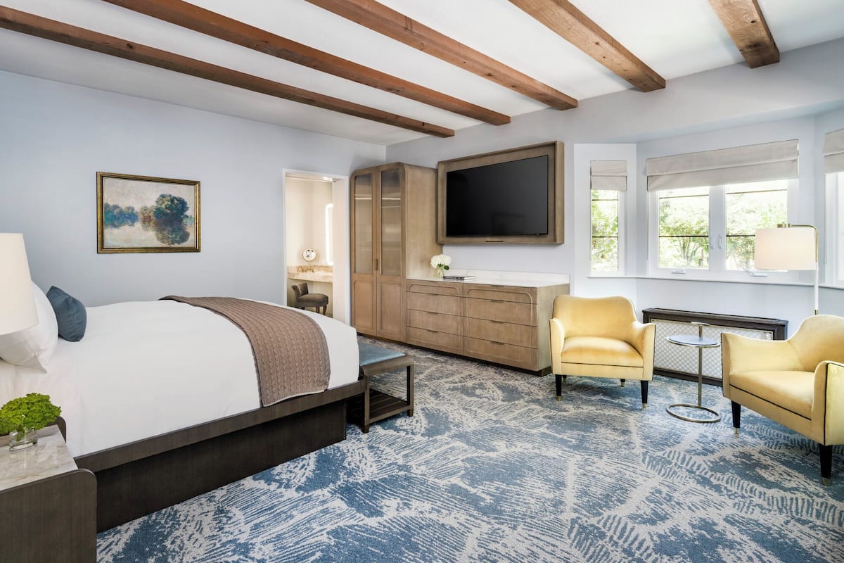 A bedroom with a bed, a TV, a wardrobe, a desk, and a chair.