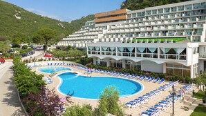 Um hotel com uma piscina grande, várias varandas e um cenário montanhoso.