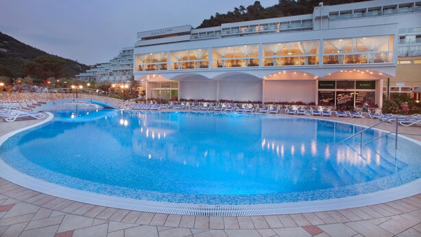 Um hotel com uma piscina grande, várias varandas e fachada bem iluminada.