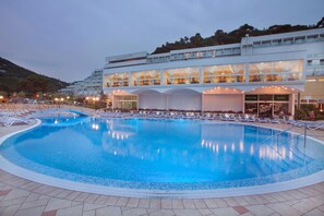 Un hôtel doté d’une grande piscine, de nombreux balcons et d’une façade bien éclairée.