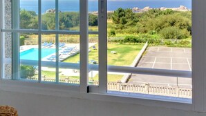 Una habitación con un ventanal grande que da a una piscina y un estacionamiento.