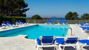 Piscina con sillas azules y una vista despejada del mar.