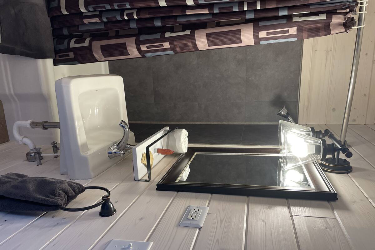 Une salle de bain avec une baignoire, une serviette, un miroir et un luminaire.