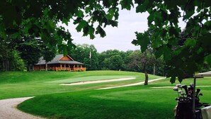 Een golfbaan met een clubhuis, een grindpad en een golfkar.