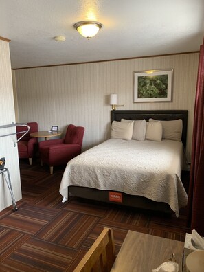Une chambre d’hôtel avec un lit, un bureau, une chaise et une petite table.