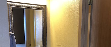 A bathroom with a granite countertop sink, dark cabinets, a large mirror, and wooden walls.
