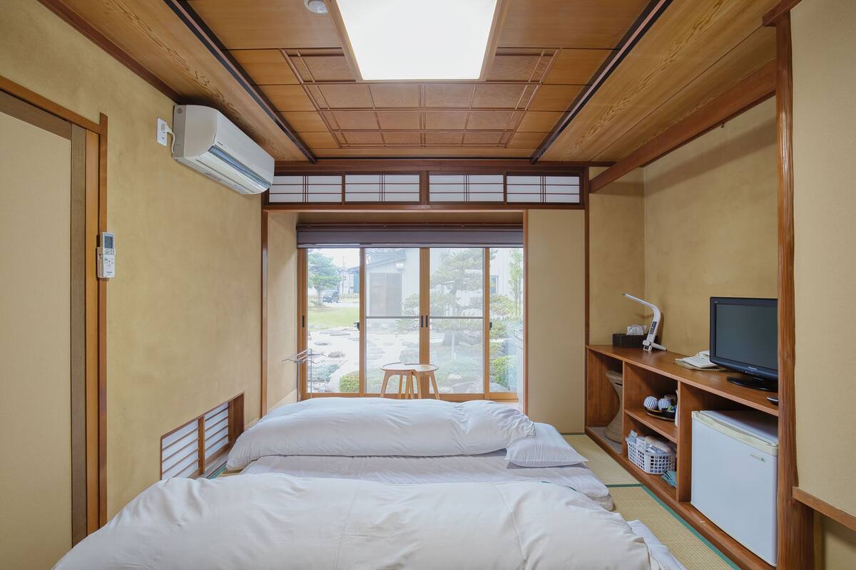 A room with a bed, a TV, a small table, and a window with a view.