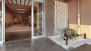 A modern interior with a sliding glass door entrance, a wooden ceiling, and a stone water feature. - Katsuzakikan (Tsubata)