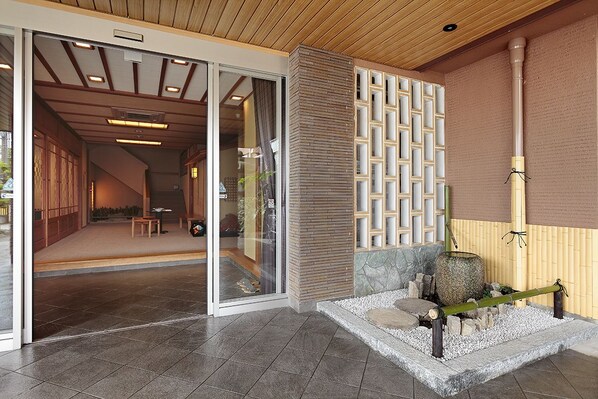 A modern interior with a sliding glass door entrance, a wooden ceiling, and a stone water feature.