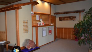 A reception area with a wooden reception desk, a large rock, and a potted plant. - Katsuzakikan (Tsubata)
