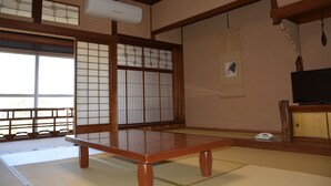 A traditional Japanese room with tatami flooring, a low wooden table, sliding shoji doors, and a television on a wooden stand. - Katsuzakikan (Tsubata)