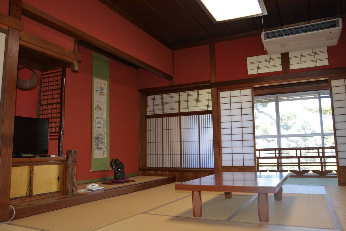 A traditional Japanese room with tatami flooring, a low table, a television, and sliding doors.