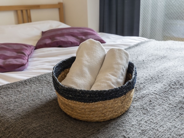 A bed with a woven basket containing two towels.