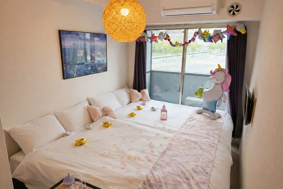 Ett hotellrum med en stor säng, en tavla på väggen, en hängande lampa och utsikt över omgivningarna.