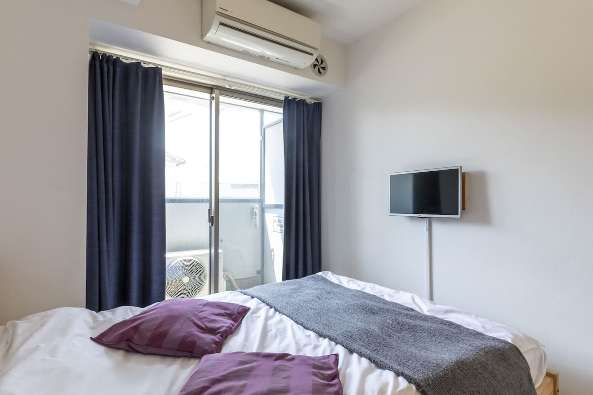 Ett hotellrum med en säng, en TV och en luftkonditioneringsanläggning.
