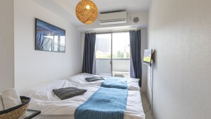 A bedroom with a bed, a window with curtains, an air conditioning unit, a wall-mounted fan, and a hanging light fixture. - Tabist Gloire Osaka (Osaka)