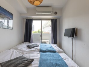 Quarto pequeno e bem arrumado com cama, televisão e ar condicionado.