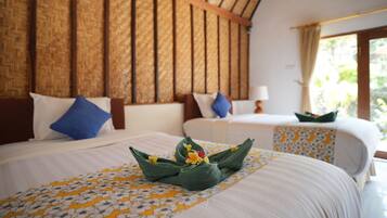 Habitación de hotel con dos camas, cada una con cubrecama y almohadas estampadas con motivos florales. La habitación tiene techo de madera y una ventana con cortinas.