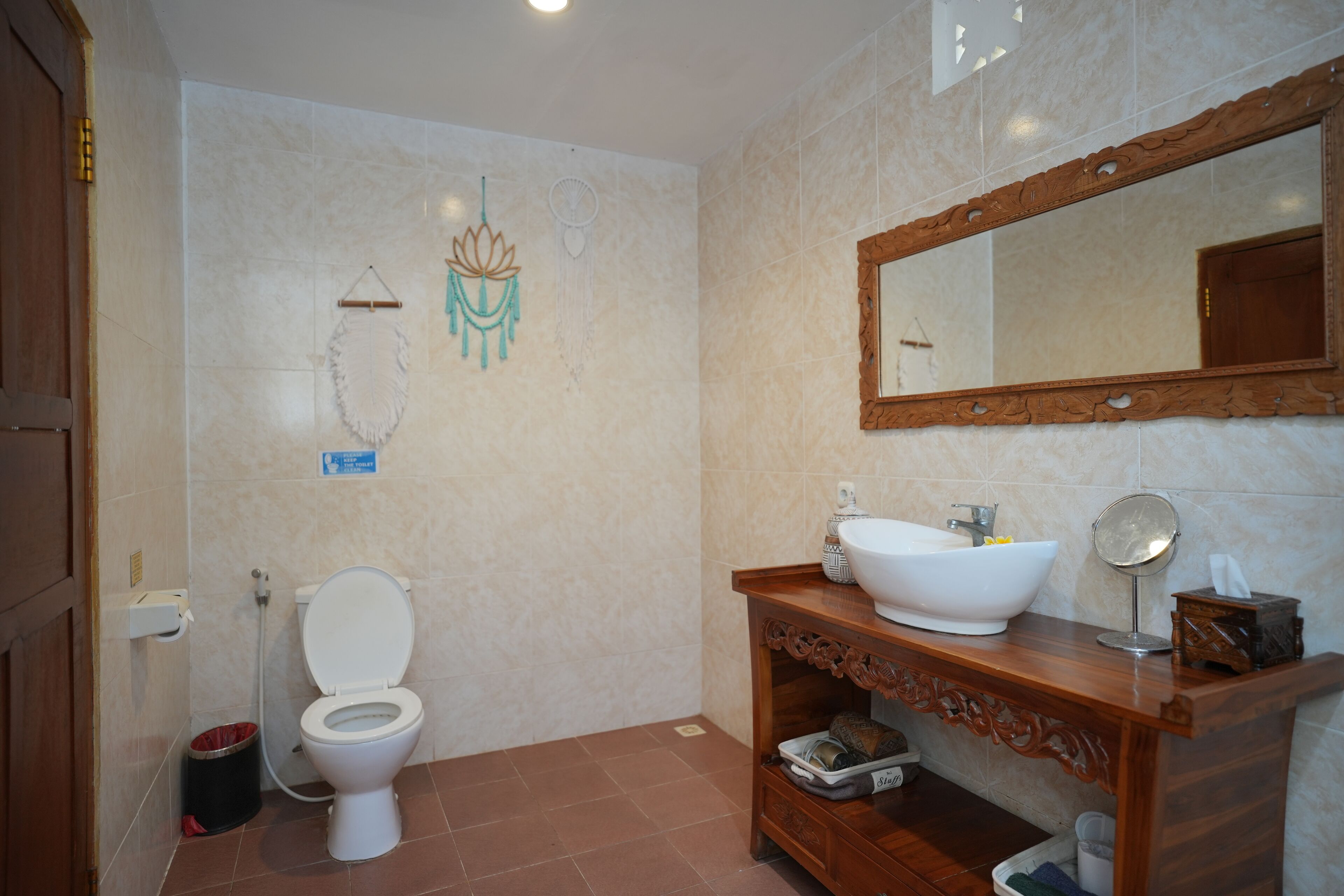 Un baño con inodoro, lavamanos, tocador, espejo y decoración en la pared.