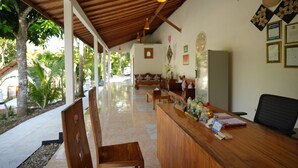 Un área de recepción con un mostrador de madera, sillas y un banco. Hay diplomas enmarcados en la pared y un ventanal que ofrece vistas al exterior.