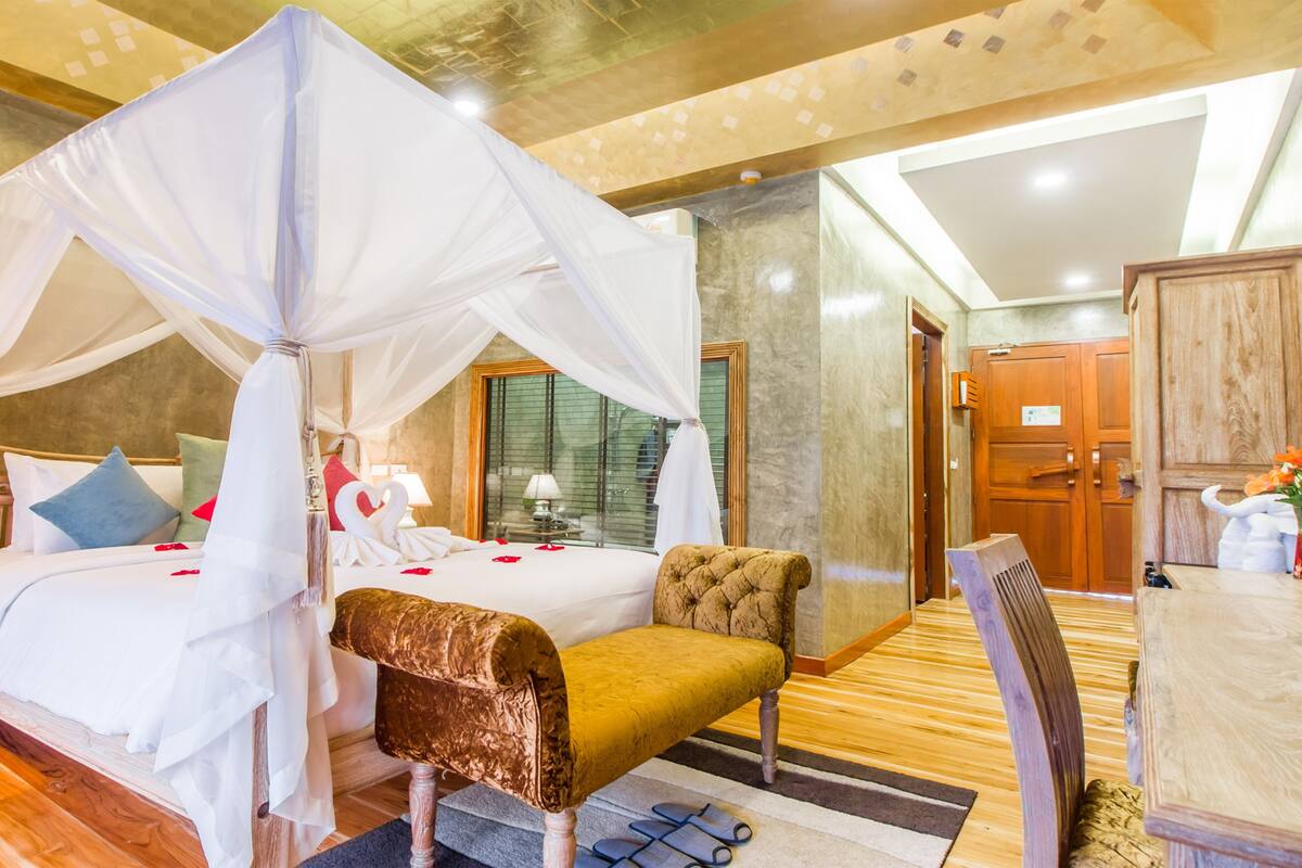 Ein Hotelzimmer mit einem Himmelbett, einer Holzbank, einem Schreibtisch und einem Stuhl.