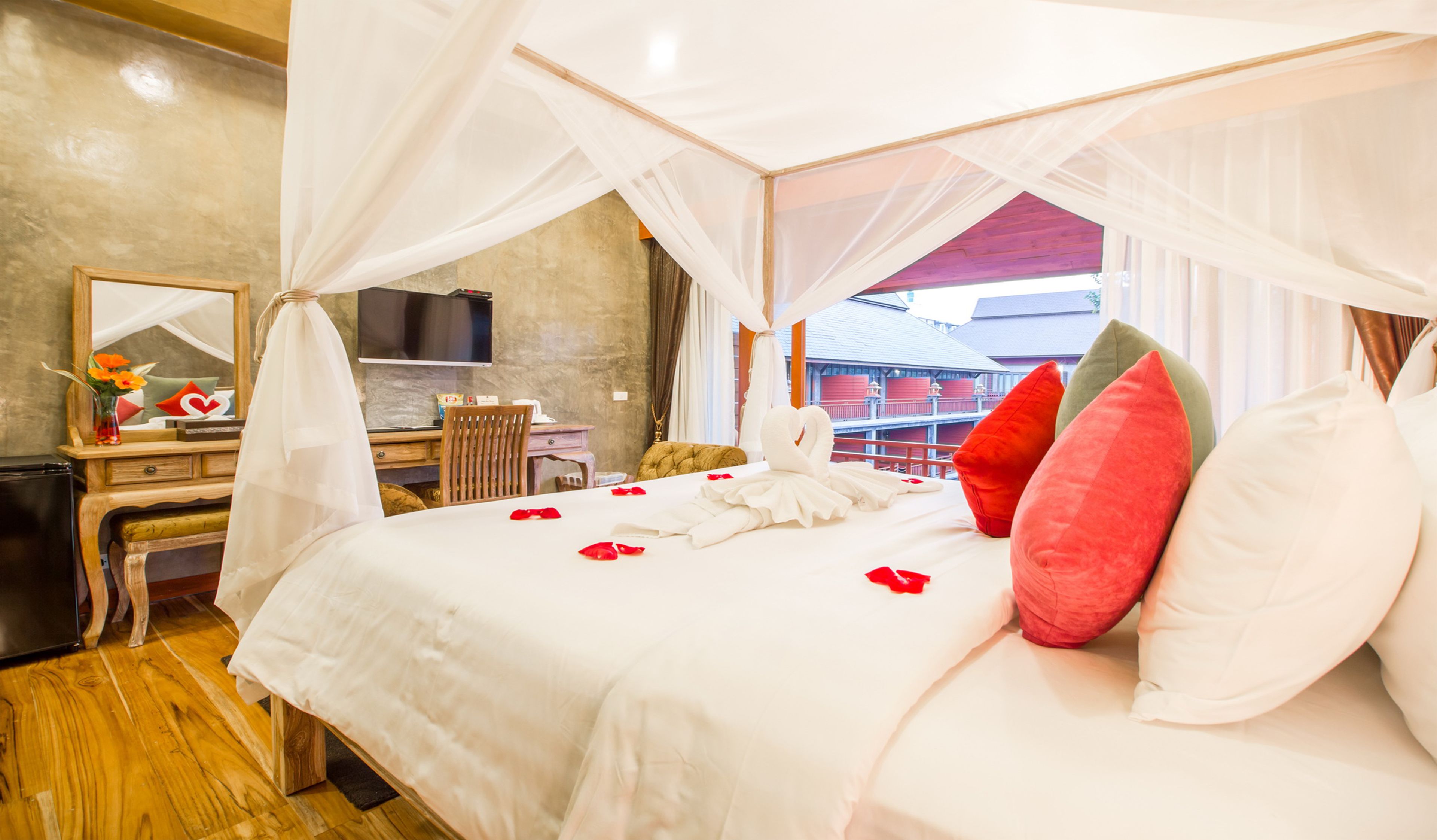 Habitación de hotel con cama, escritorio, silla, televisor y vistas a edificios.
