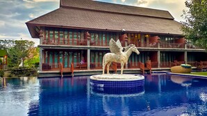Un hôtel doté d’une grande piscine, d’une statue de cheval et d’un immeuble à plusieurs étages avec des balcons.
