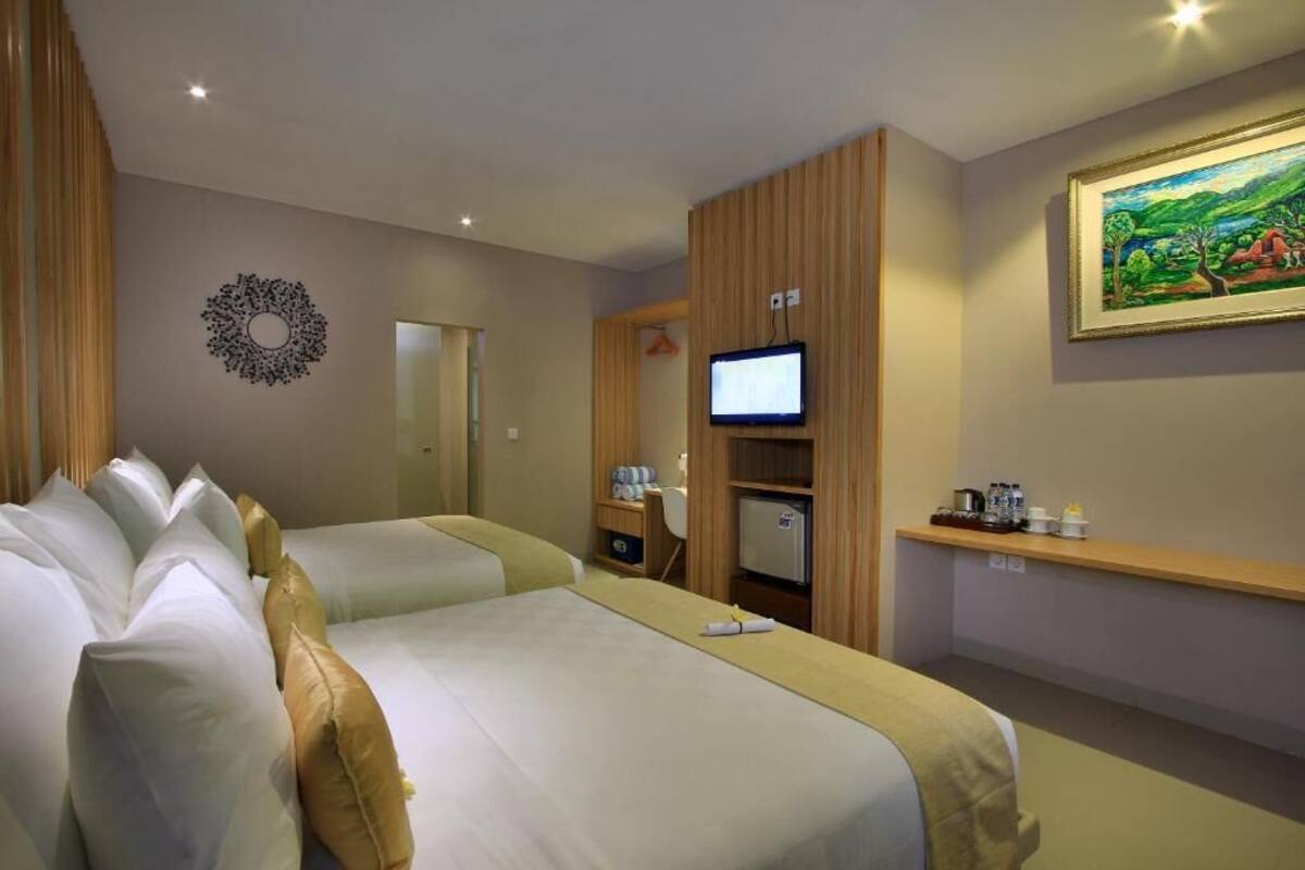 A hotel room with two beds, a television, a small refrigerator, a desk, and a painting on the wall.