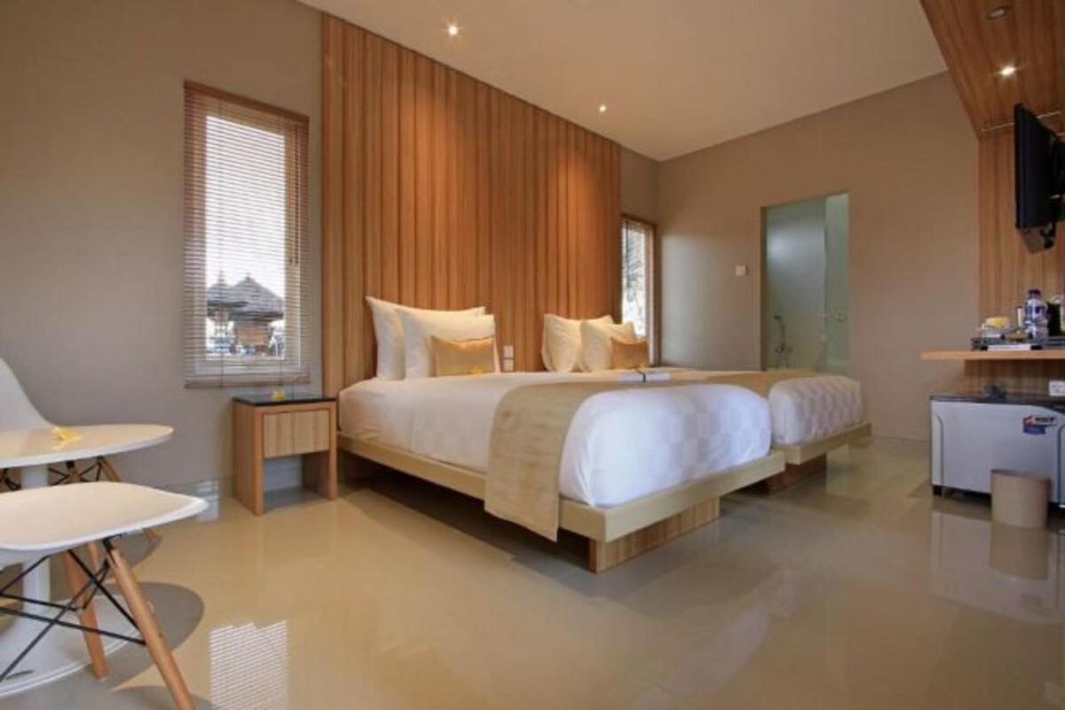A modern hotel room with a large bed, bedside tables, a small desk, and a TV.