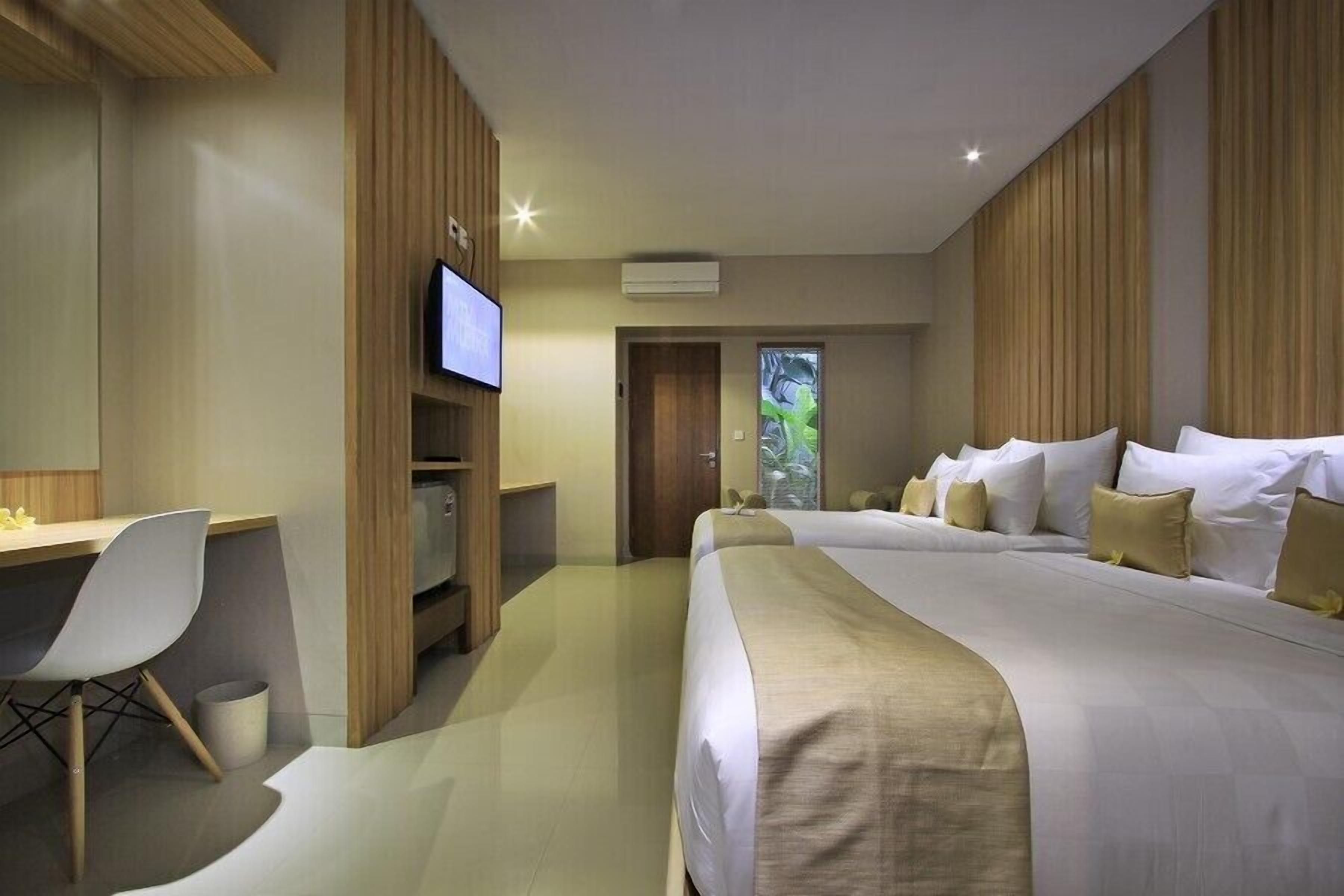 Una habitación de hotel moderna con una cama grande, un escritorio con silla, televisión y una puerta que da a un balcón.