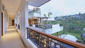 A modern hotel corridor with a balcony overlooking a lush garden.