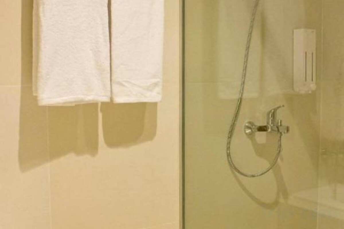 Une cabine de douche en verre avec un pommeau de douche à main et un porte-serviettes avec deux serviettes blanches.
