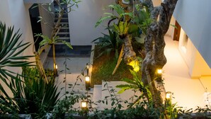 A multi-level indoor garden with various plants, a staircase, and illuminated lanterns.
