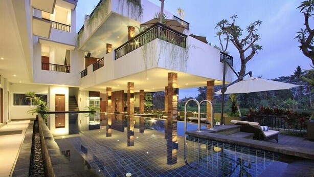 A modern multi-story building with a rooftop pool, outdoor seating, and a lush garden.