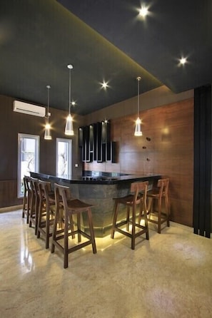 A modern kitchen with a central island, bar stools, pendant lighting, and a dark ceiling. - Puri Padma Hotel (Ubud)