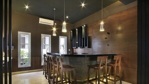 A modern kitchen with a bar area, wooden bar stools, pendant lighting, and a large window.