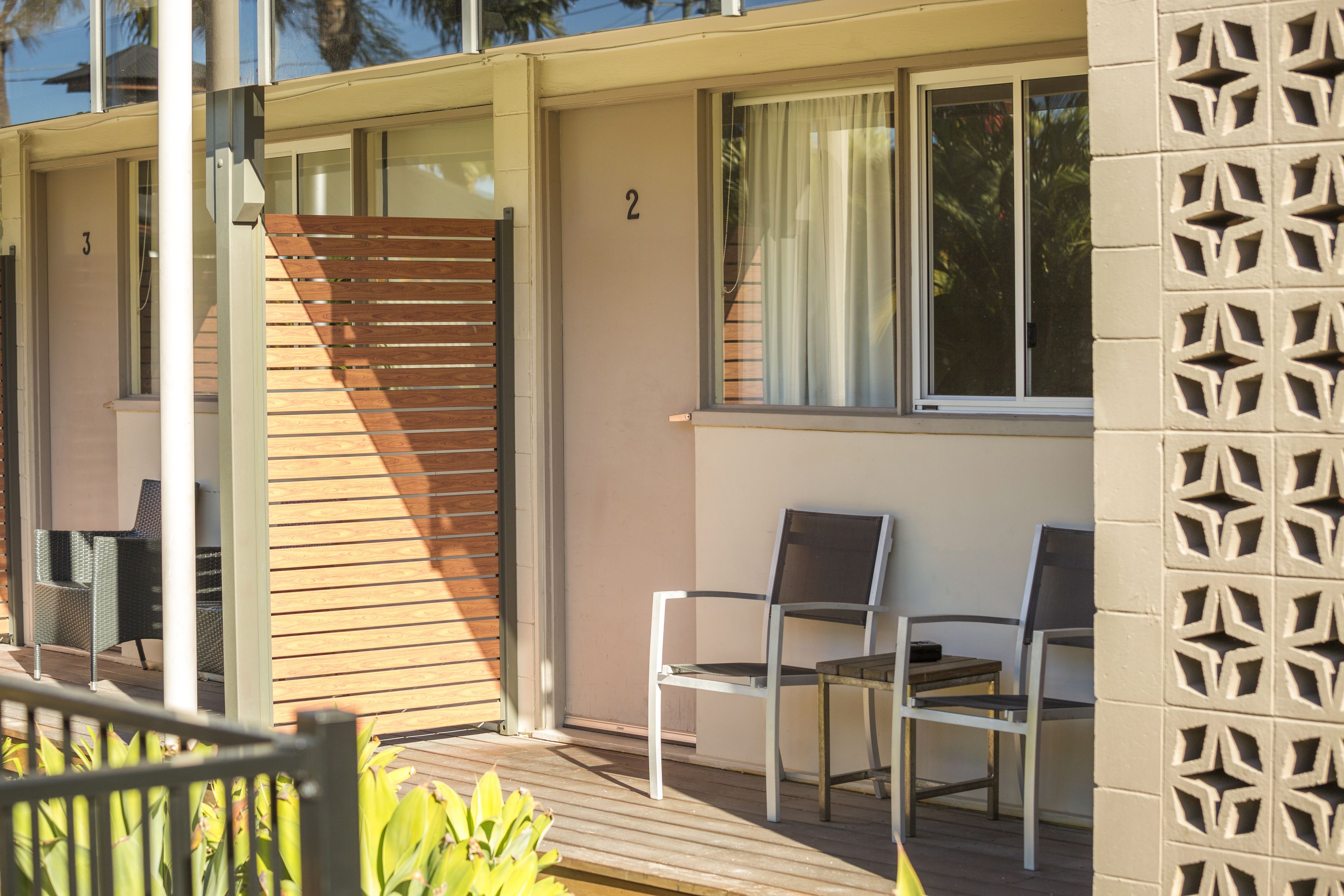A modern building with a wooden deck, numbered rooms, and outdoor seating.