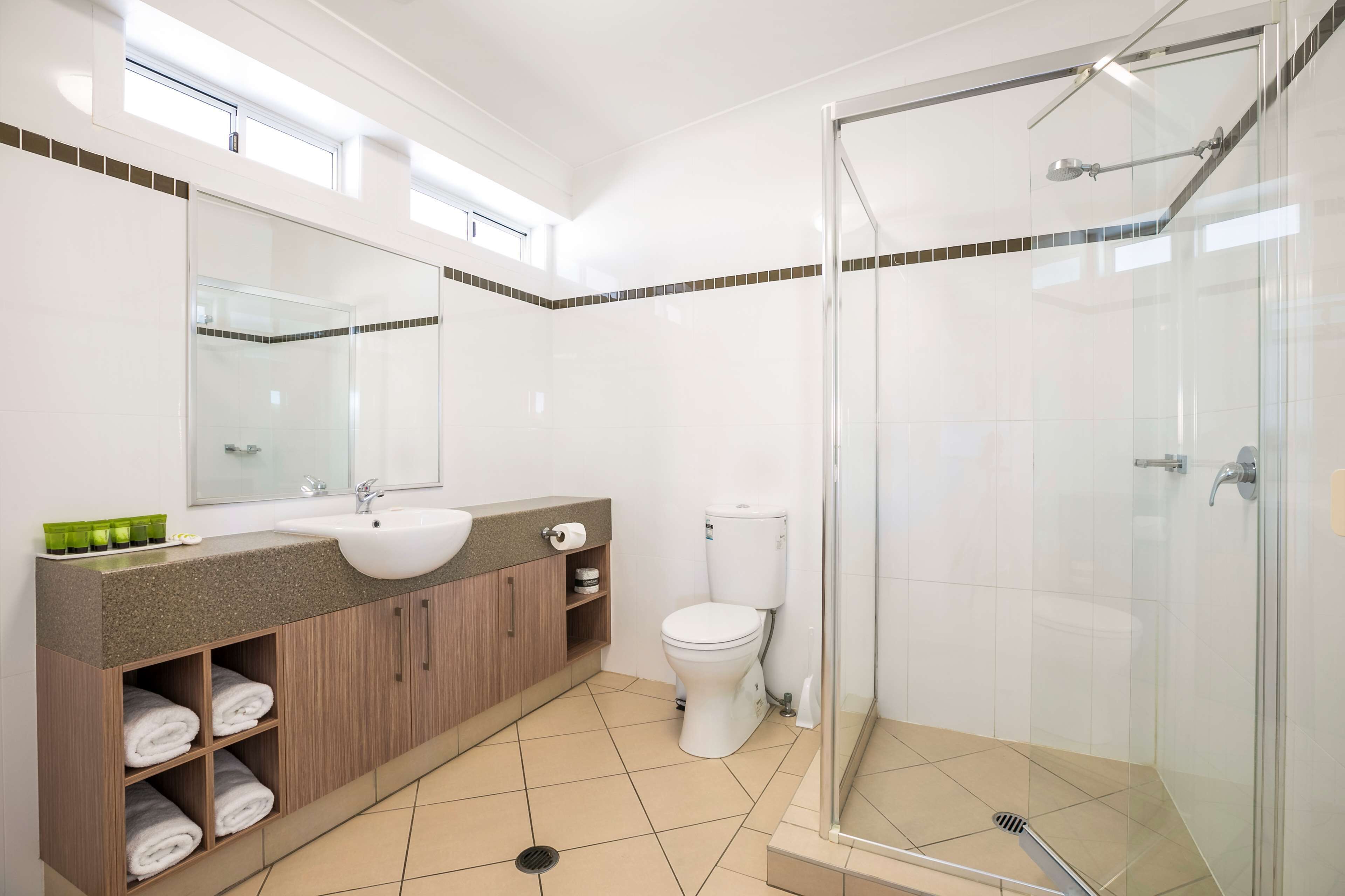 Un baño moderno con ducha de vidrio, lavamanos y retrete.