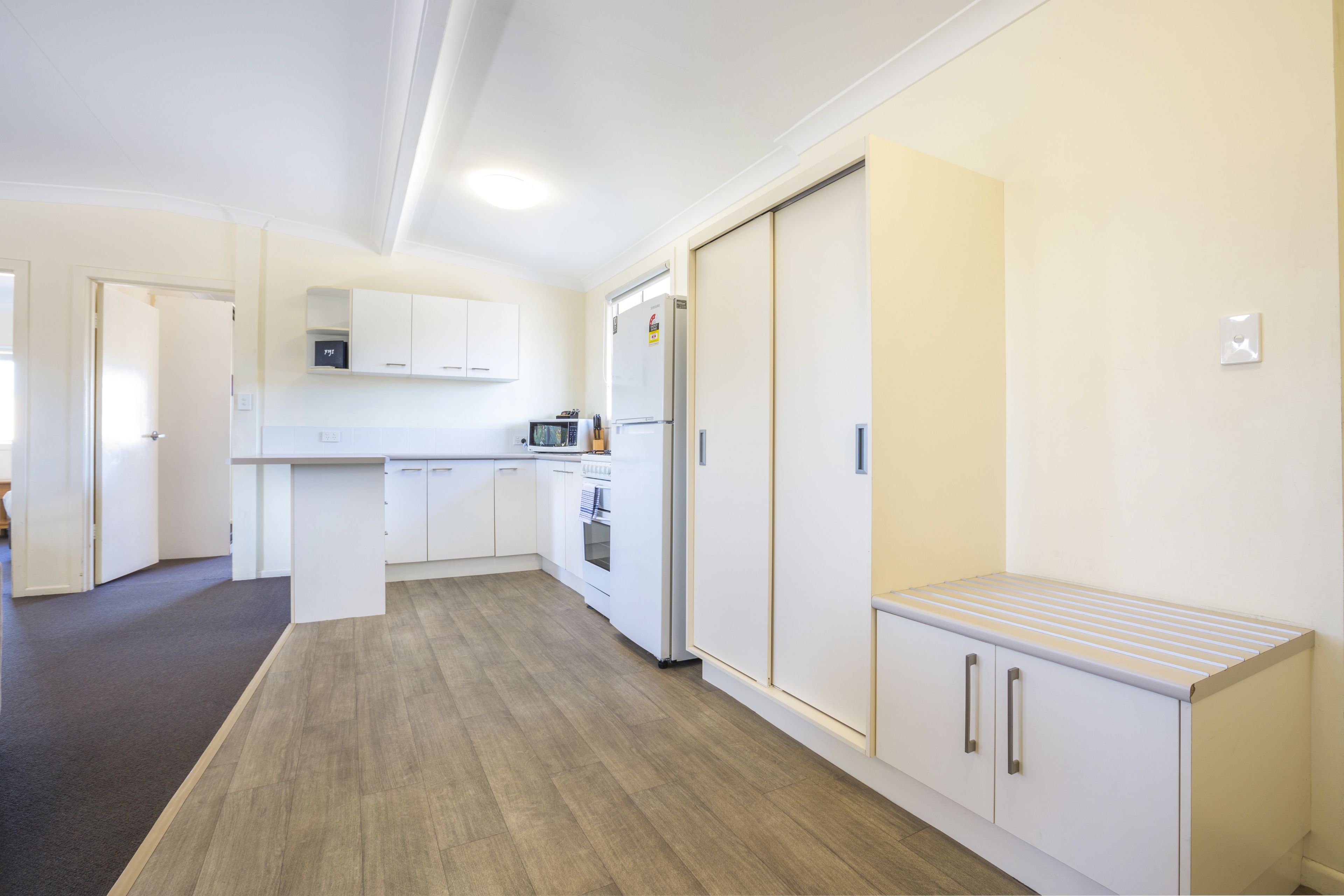 A modern kitchen with white cabinetry, a microwave, and a refrigerator.