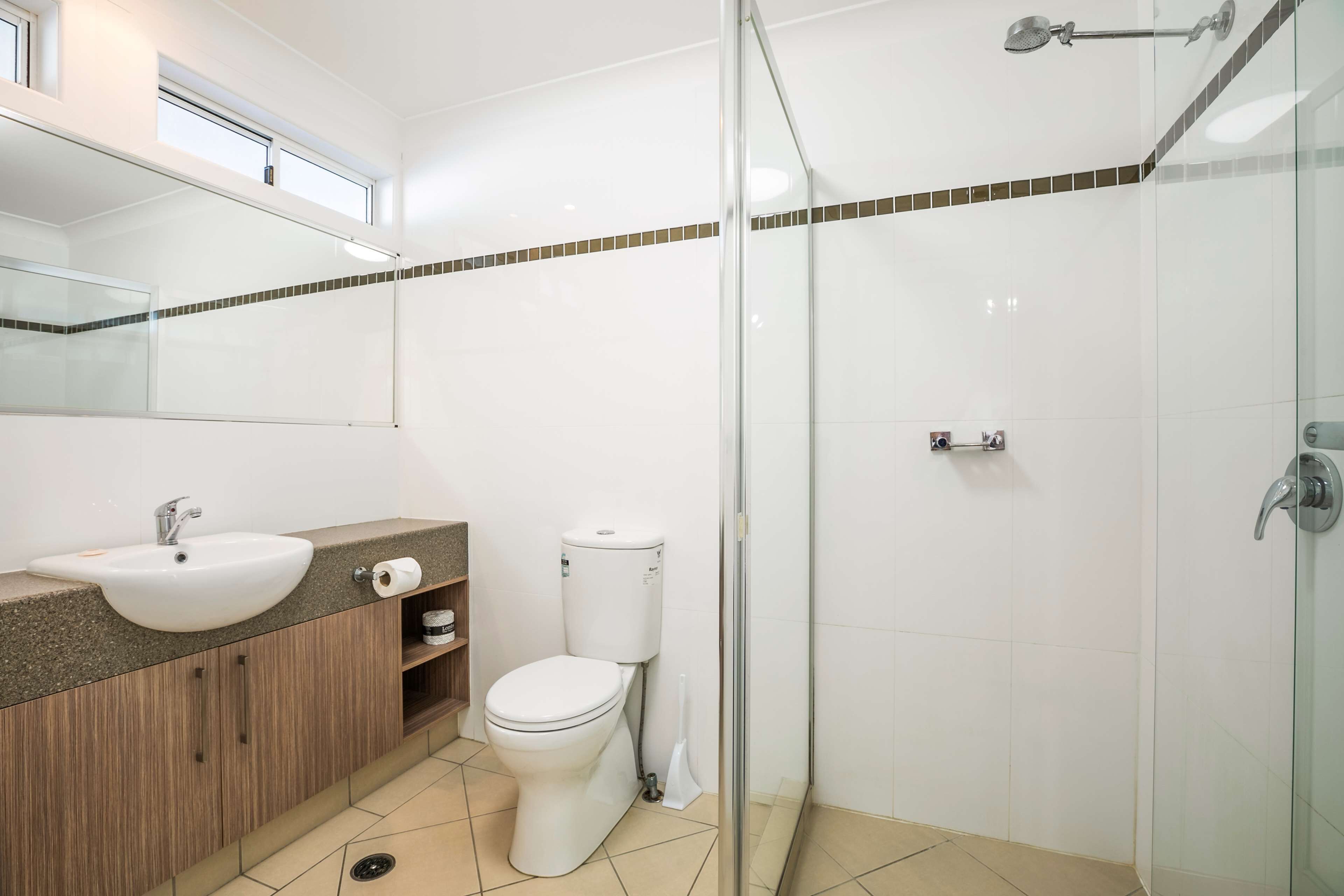 A modern bathroom with a glass shower enclosure, a sink with a mirror above, and a toilet.