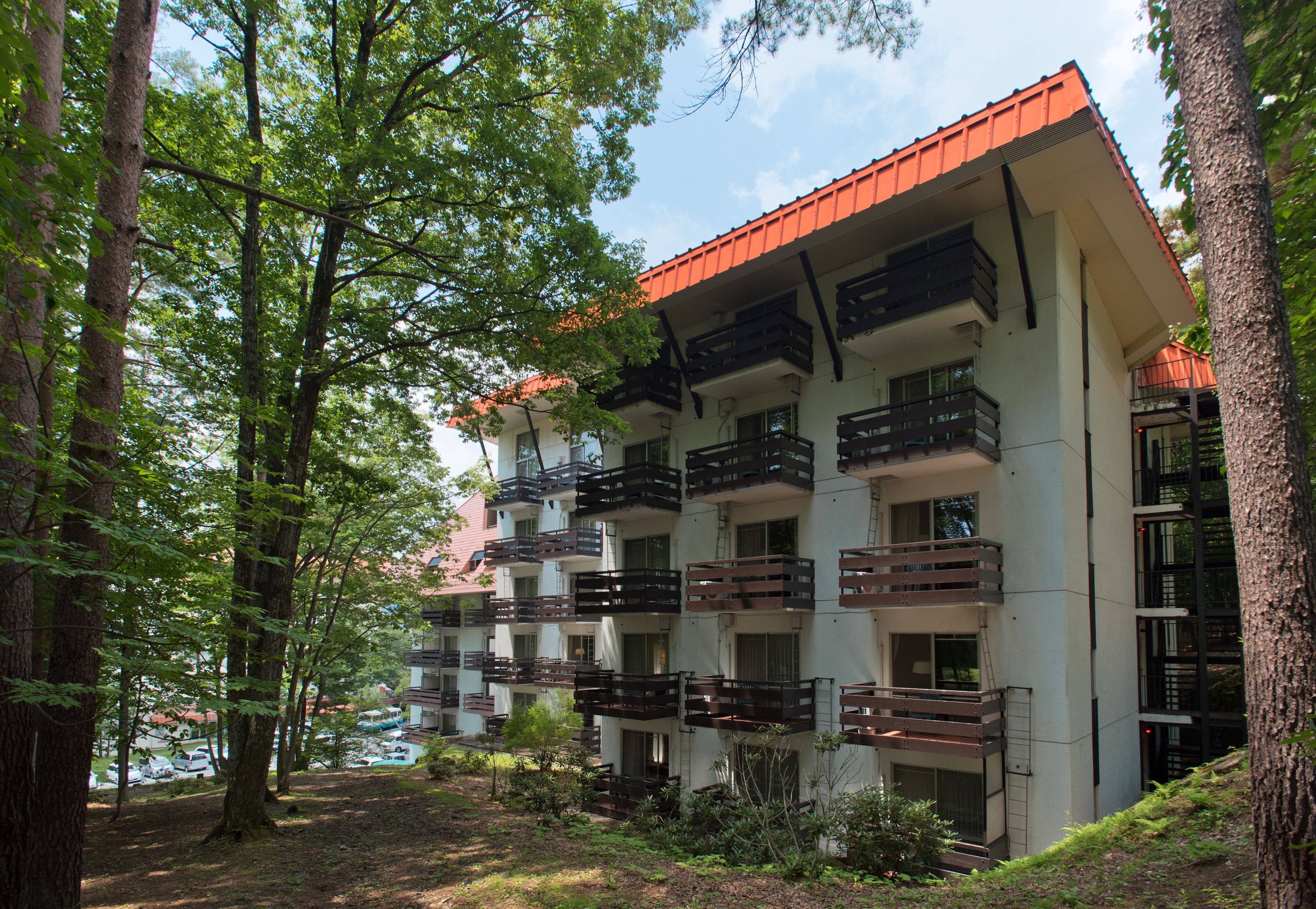 Un immeuble à plusieurs étages doté de balcons, entouré d’arbres.