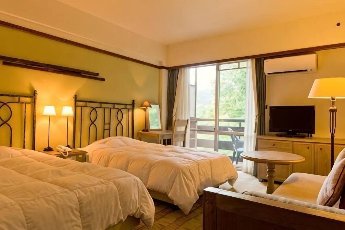 Een hotelkamer met twee bedden, een televisie, een bureau en een balkon met uitzicht.