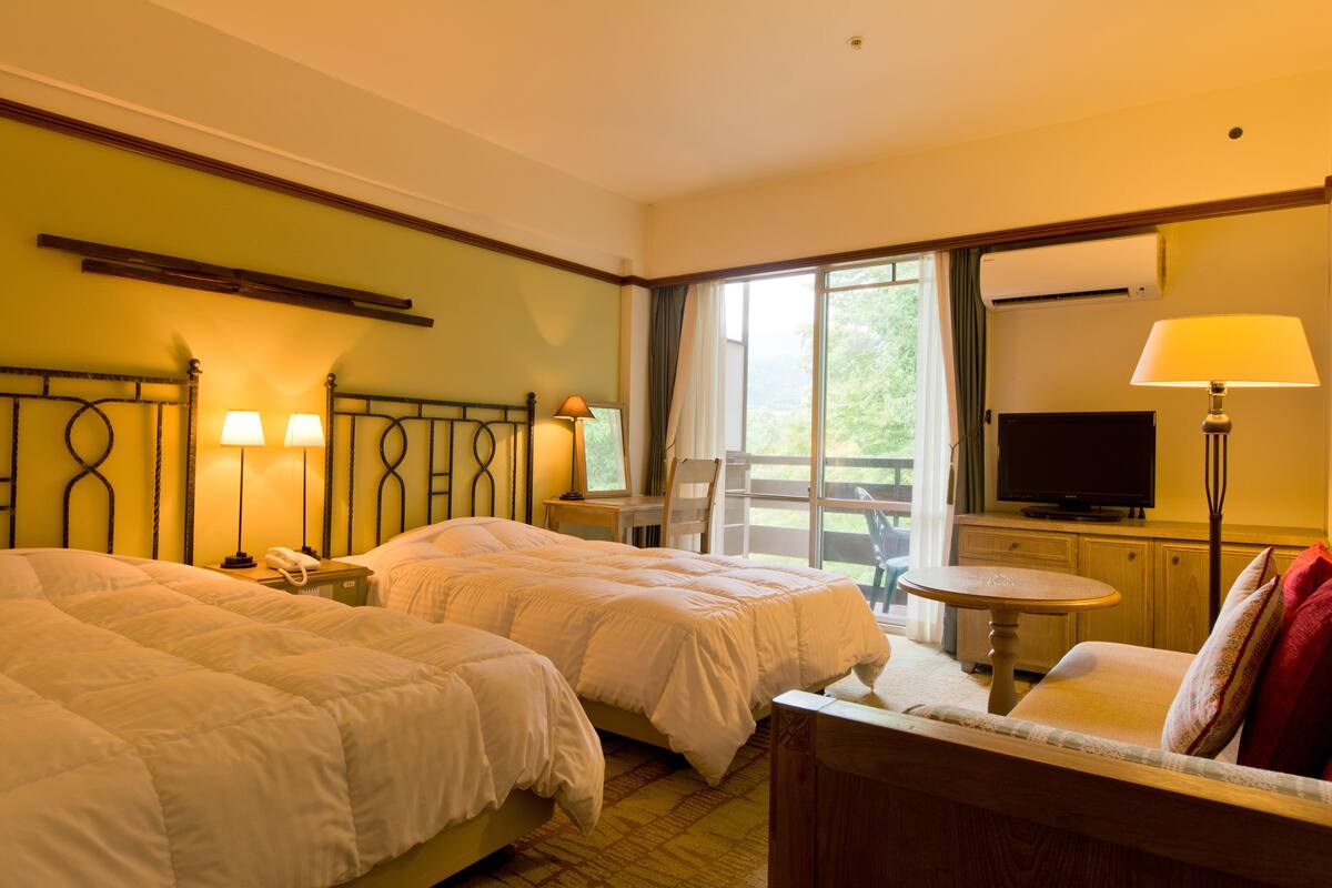 Een hotelkamer met twee bedden, een televisie, een bureau en een stoel.