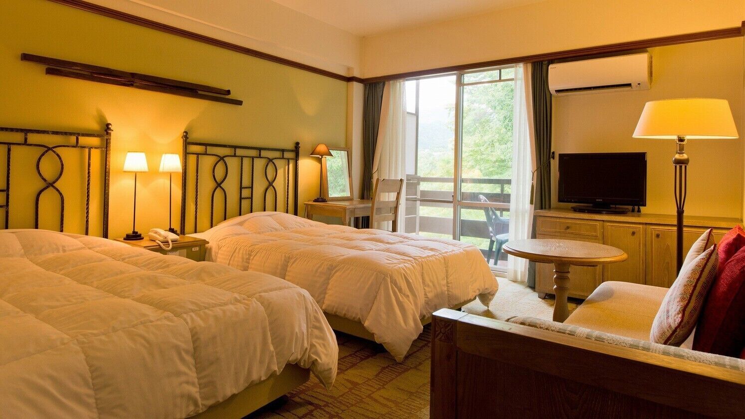 Ein Hotelzimmer mit zwei Betten, einem Fernseher, einem Schreibtisch und einem Stuhl.