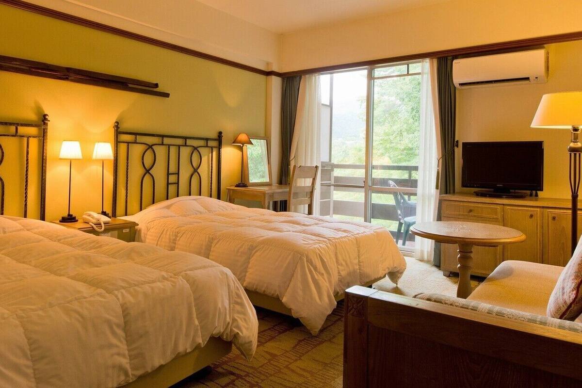Een hotelkamer met twee bedden, een televisie, een bureau en een stoel.