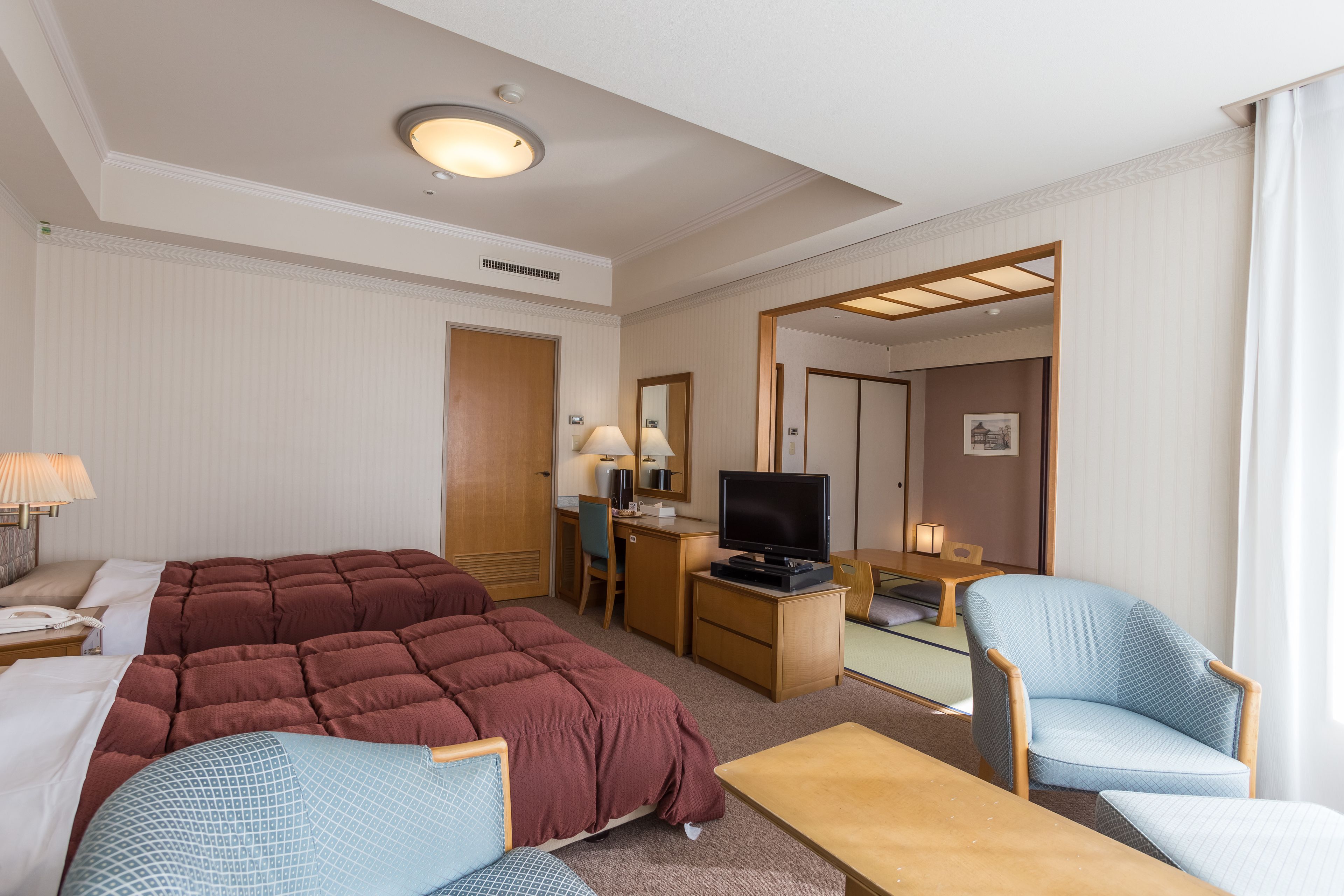 Une chambre d’hôtel avec un grand lit, un bureau avec une télévision, une chaise et une petite table.